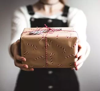 A woman giving a gift in brown wrapping paper